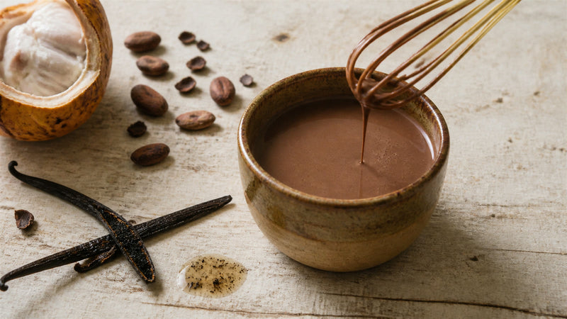 Smooth ceremonial cacao with split vanilla beans and a small whisk